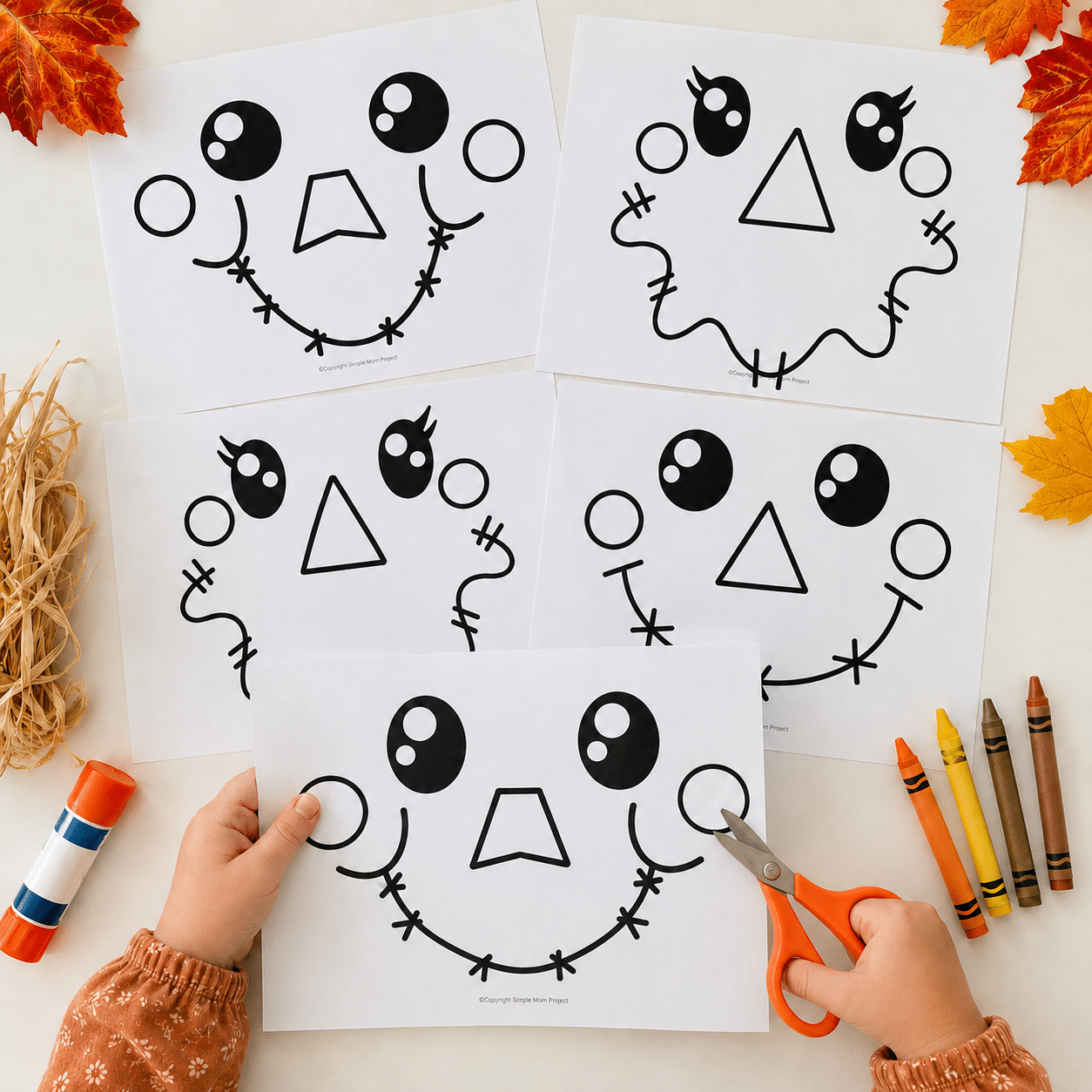 Child cutting a printable scarecrow face template surrounded by five face designs and fall craft supplies.