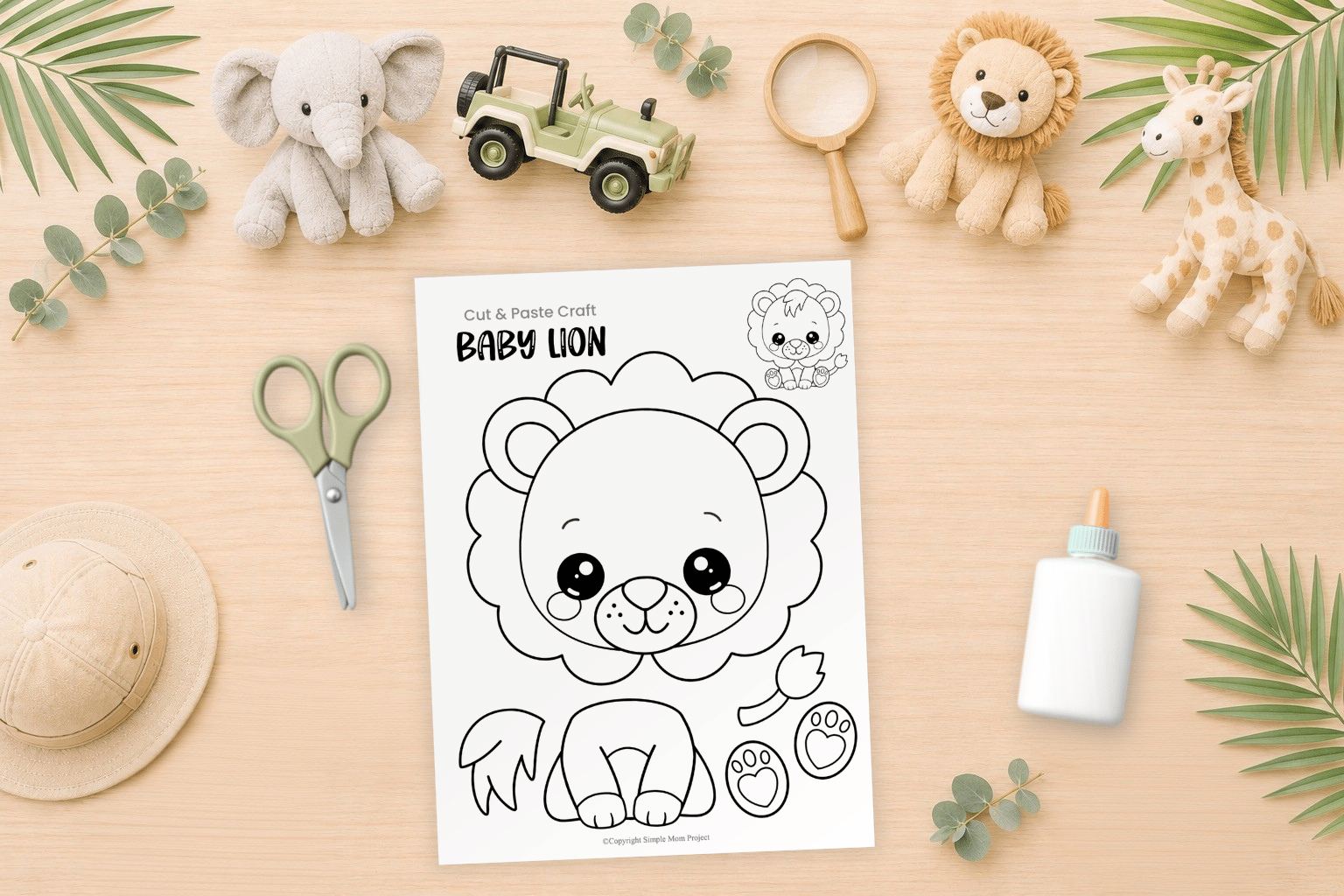 Baby lion cut and paste craft printable arranged in a preschool craft flatlay with school supplies and safari-themed materials.